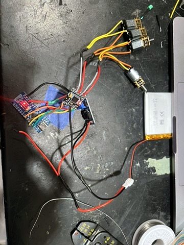 The V1 car's loose modules: motor driver, gear motors and a lithium battery wired together on a workbench